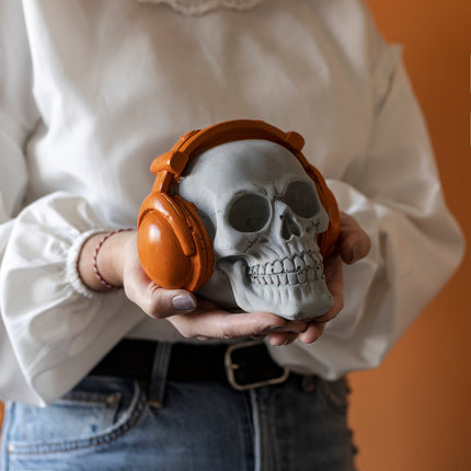 Figura de calavera naranja de hormigón con auriculares