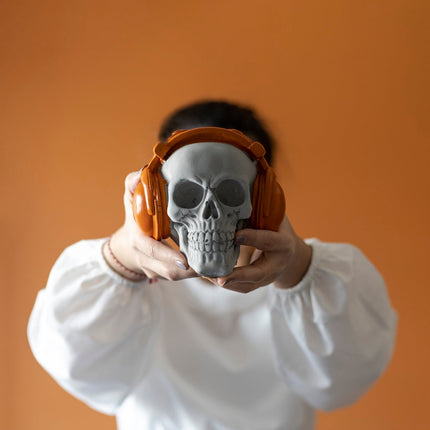 Figura de calavera naranja de hormigón con auriculares